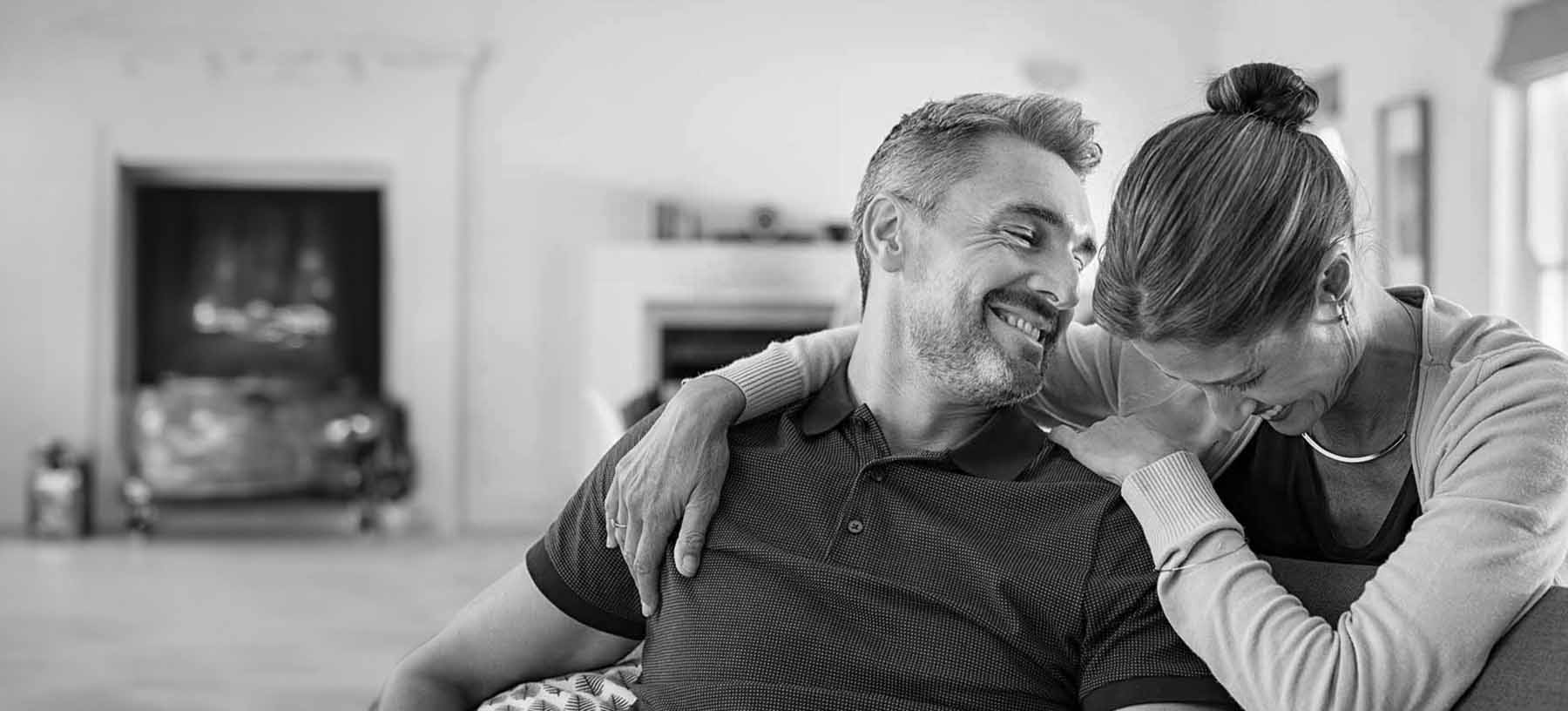 A relaxed middle-aged couple sitting together at home, reflecting the ongoing hormone care involved in BHRT at Optimal Well MD in Virginia Beach.
