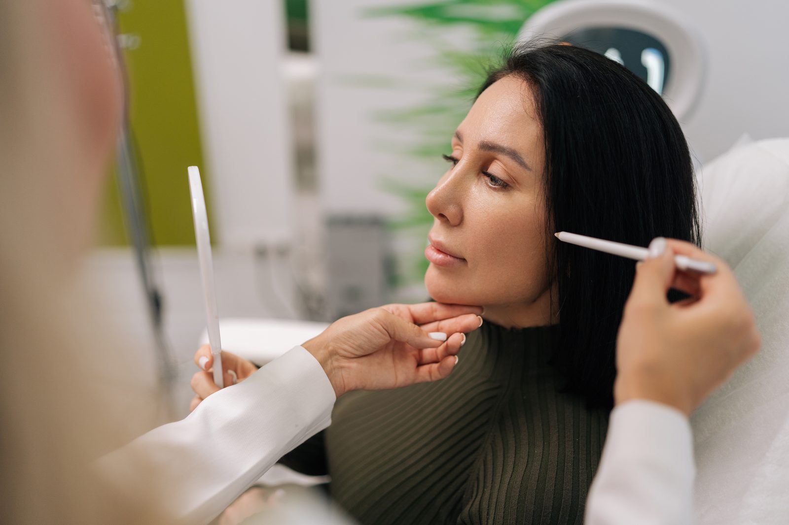 A practitioner marking a patient’s cheek and jawline with a white pencil before an aesthetic procedure, as done when planning PDO thread lift vectors in Virginia Beach