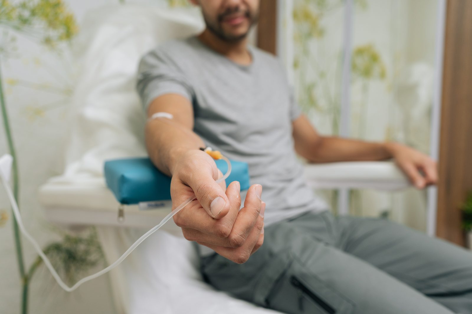 A seated patient receiving an intravenous vitamin infusion through a drip line in their arm in a bright clinic room, representing IV therapy in Virginia Beach