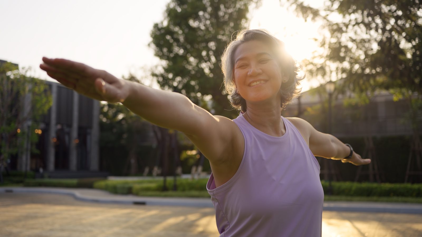 A smiling middle-aged woman stretching outdoors in warm evening light, representing an active approach to managing menopause-related weight gain in Virginia Beach